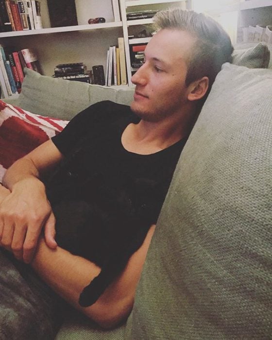 hombre abrazando a un gato negro