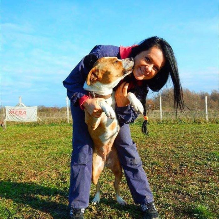 mujer feliz abrazando a un perro en un campo deportivo