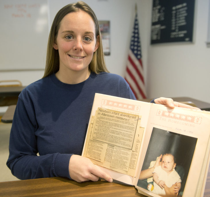 Mujer sosteniendo un album con su foto y la noticia de como su mamá la abandonó