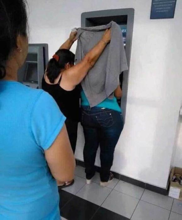 Mujer cubriendo el cajero con un sueter