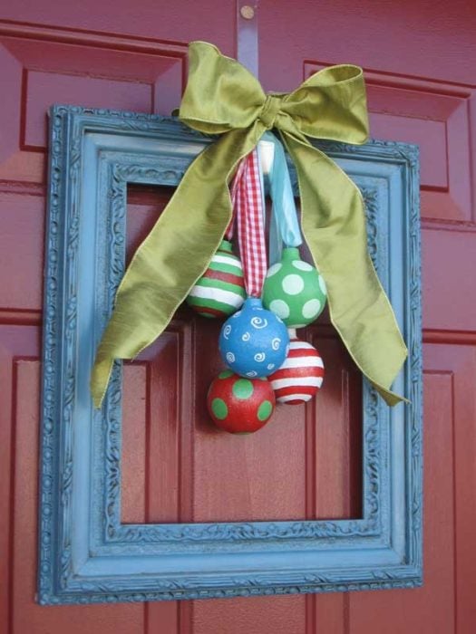 marco de madera con esferas y moño decoracion navideña en la puerta