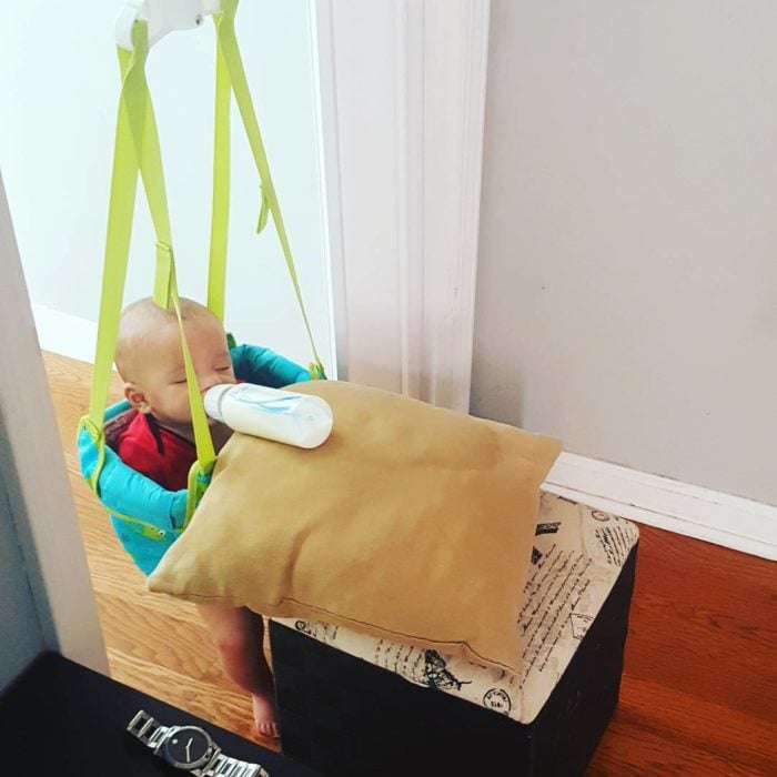 niño bebiendo de biberón sostenido por una almohada