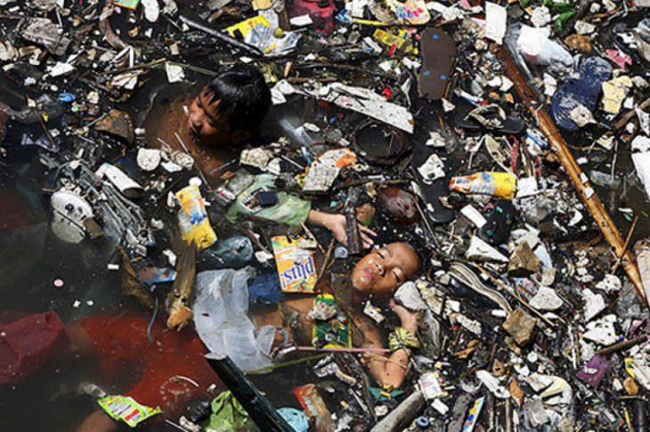 niños nadando en el mar lleno de basura