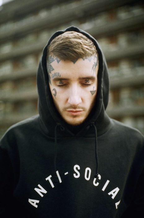 muchahco con sudadera negra y el rostro tatuado