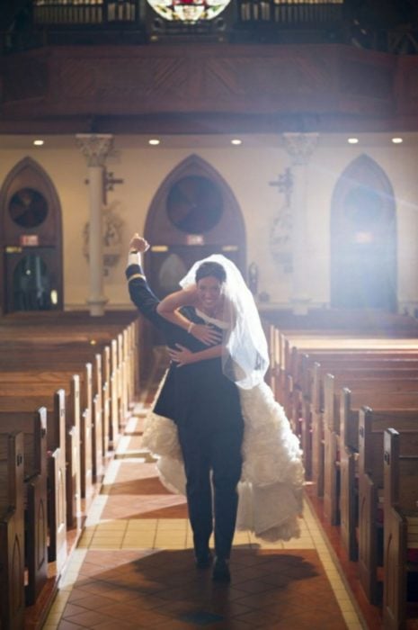 novio carga a la novia para fuera del altar