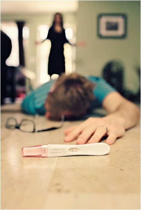 chico en el suelo tirado, frente a él está una prueba de embarazo y detrás una mujer