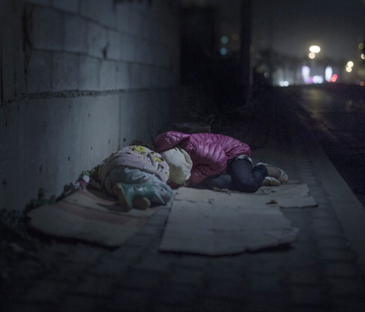 Dos niñas durmiendo sobre cartones en la calle