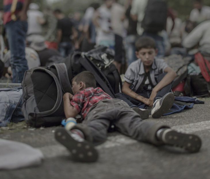 Niño sirio dormido sobre mochilas en medio de la calle