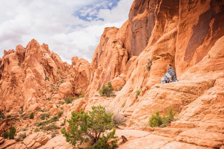 mujer sentada en paisaje rocoso 