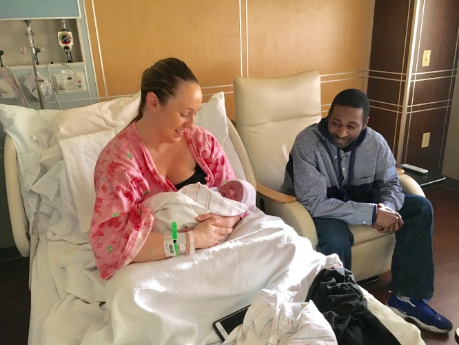 Mujer en el hospital con bebé recién nacido y su esposo al lado