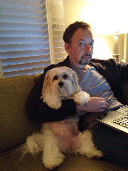 papa en la computadora abrazando al perro