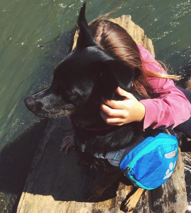 Chica abrazando a otra perrita negra