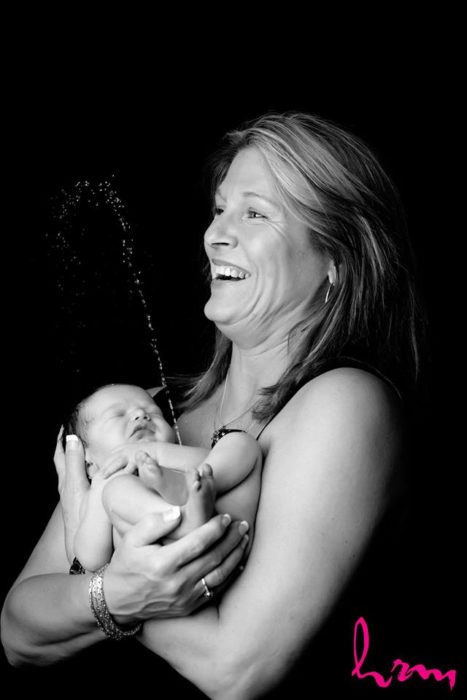 señora sonriendo mientras su bebé se hace pipí en sus brazos