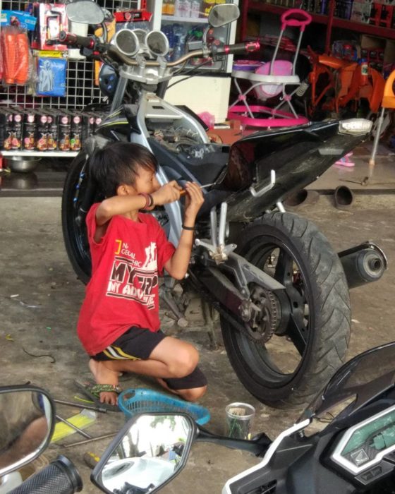 niño arreglando una moto