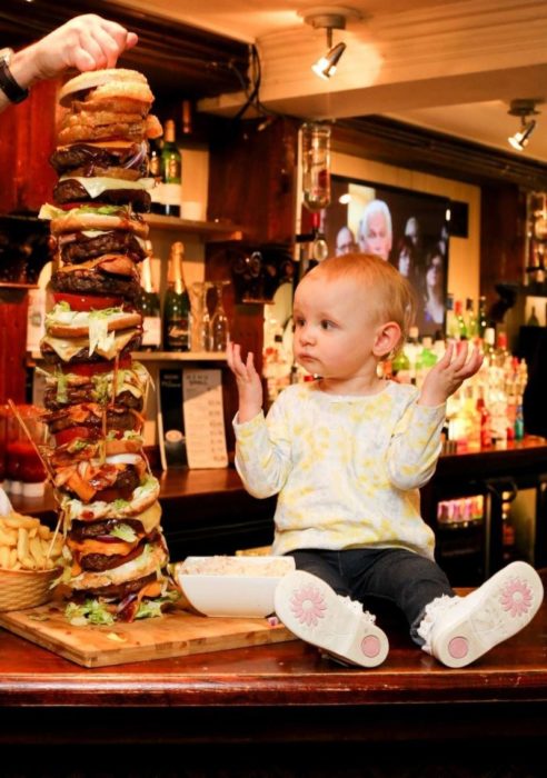 una niña junto a una hamburguesa enorme