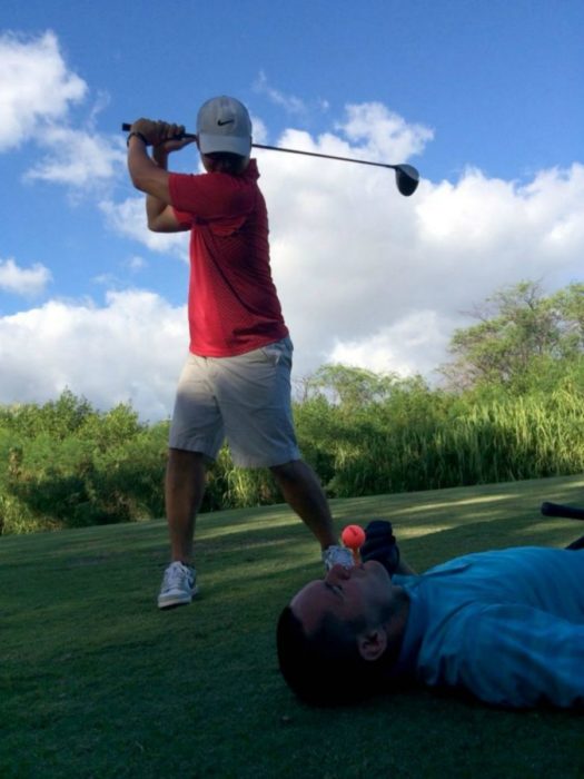 hombre a punto de golpear la pelota que está sobre otro hombre