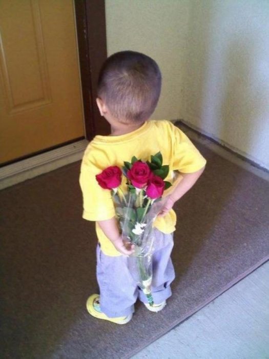 niño sostiene en la espalda un ramo de flores