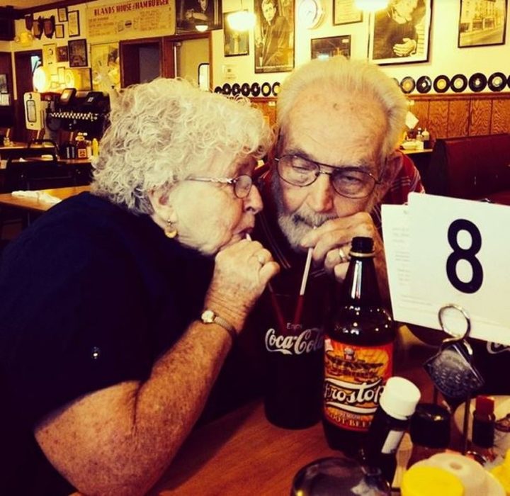 Pareja mayor tomando refresco con dos popotes