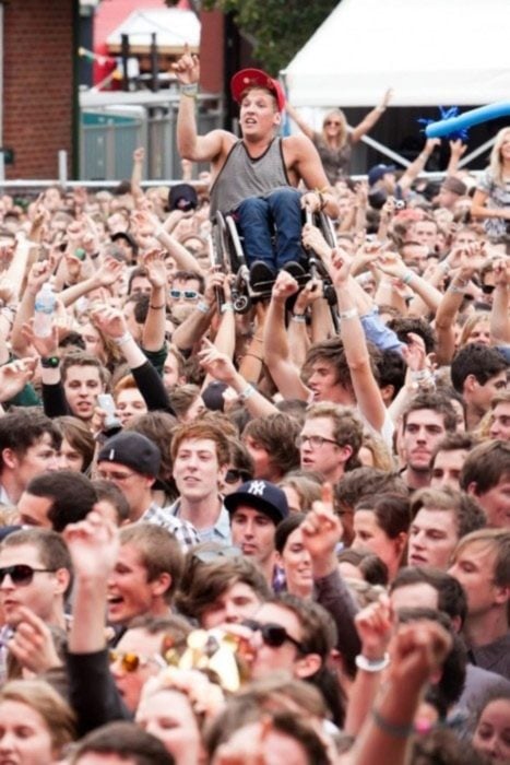 foto de concierto y todos levantan a chico en silla de ruedas