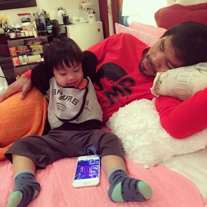 Manny Pacquiao y su hijo acostados viendo el celular