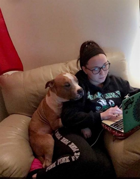 chica estudiando y perro al lado abrazándola