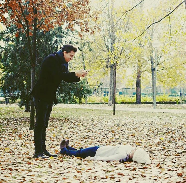 mujer recostada sobre las hojas mientras hombre le toma foto