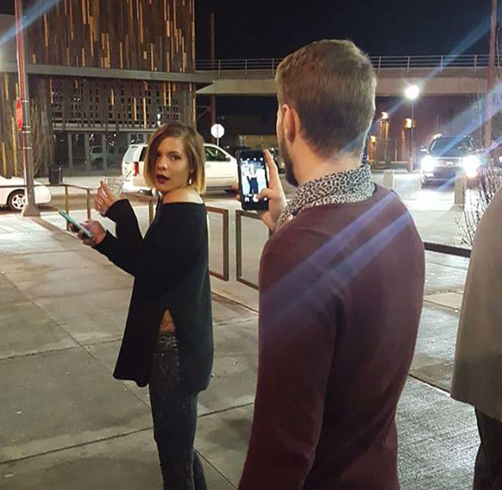 chico tomando una foto a su novia bajo la luz de la calle