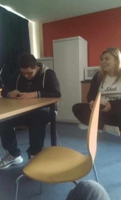 chico sentado en una mesa y chica sentada en una alfombra