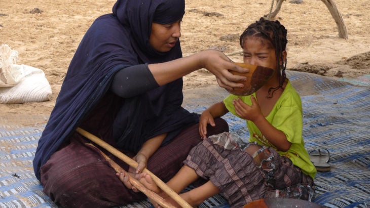 mujer forza a una niña a comer en áfrica