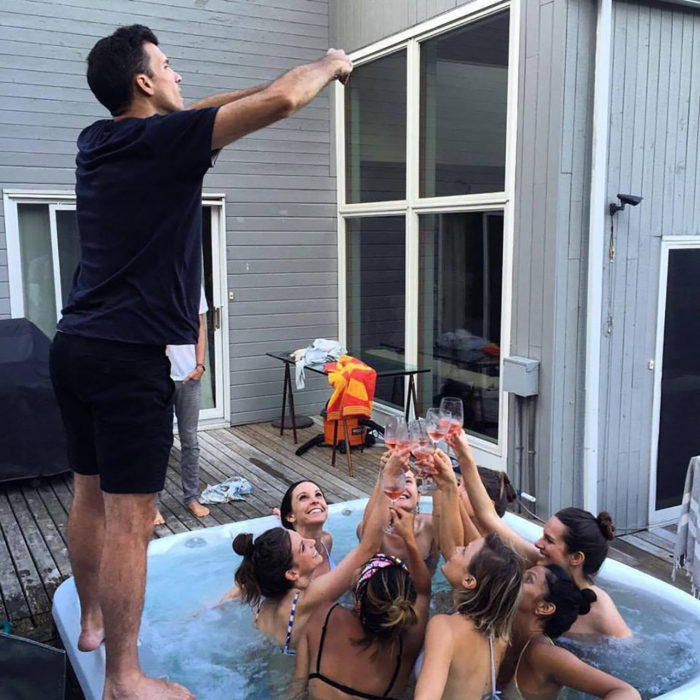 hombre tomando fotos a mujeres levantando sus copas en jacuzzi