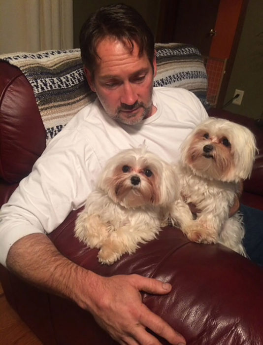 hombre con dos perros peludos