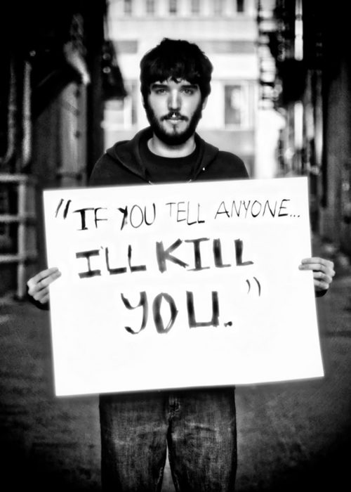 hombre sostiene cartel que dice te mataré si le dices a alguien