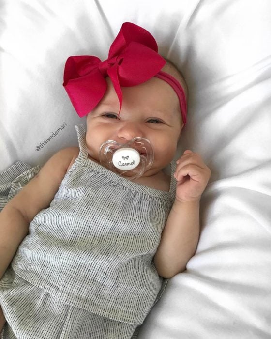 bebe sonriente con moño rojo