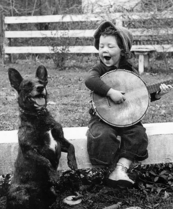 niña tocando con su banjo a un lado del perro