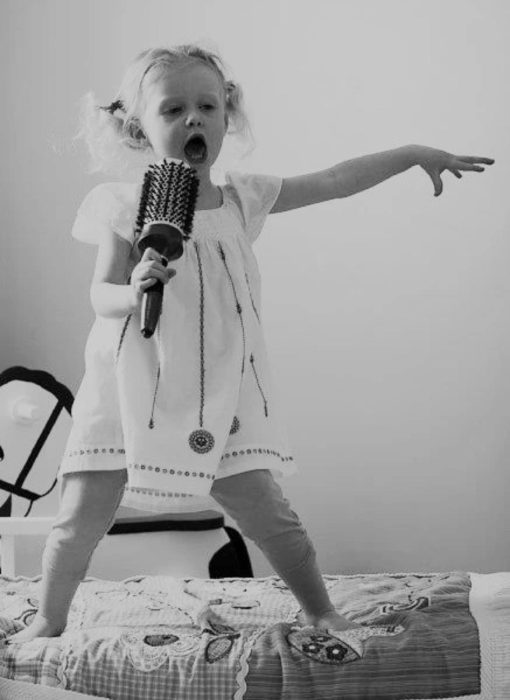 niña cantando con un cepillo