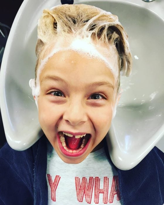 niño sonriendo con champú en el cabello 