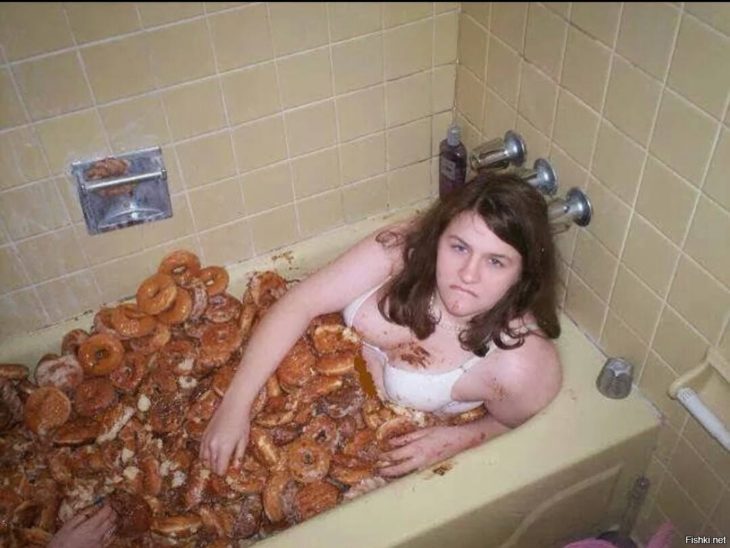 mujer en bañera llena de donas