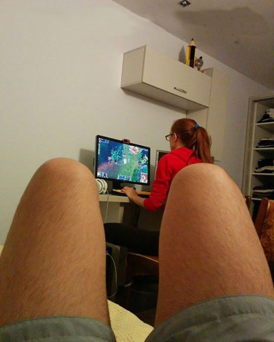 mujer jugando vídeojuegos mientras su novio enseña las piernas