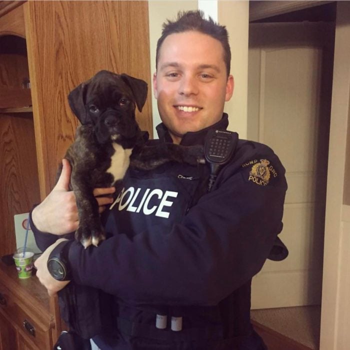 policía sonriendo y cargando un cachorro