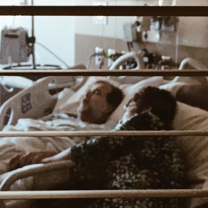 hombre en cama de hospital y mujer a su lado