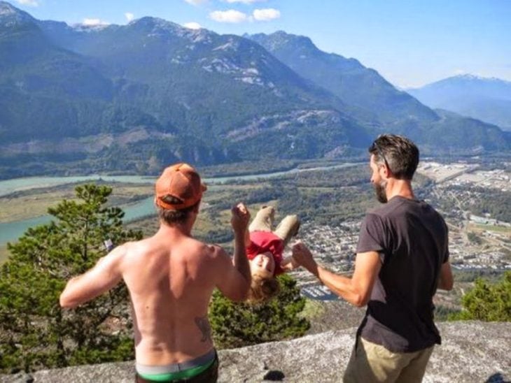 dos hombres columpiando a una niña en las montañas