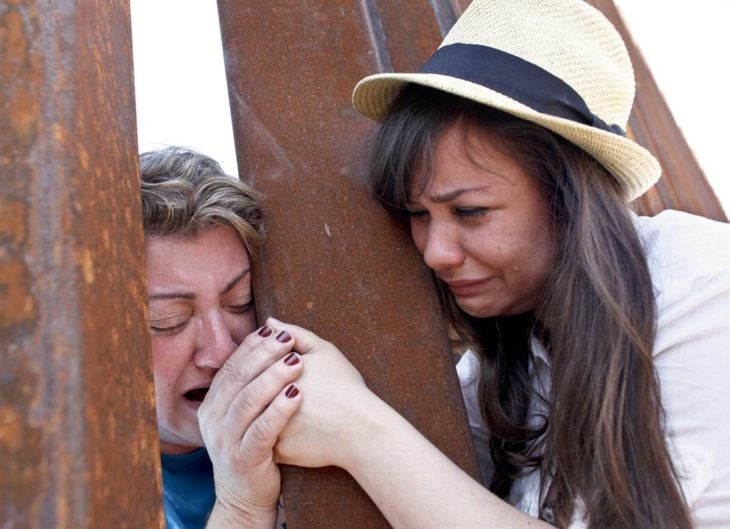 mujer sostiene la mano de su madre en la frontera