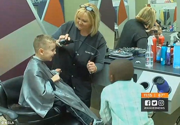 niño en una estética sentado en una sila mientras una mujer le corta el cabello