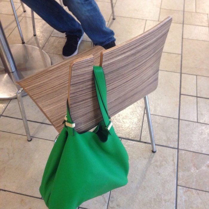 Silla con ranura para sostener bolsos con un bolso verde