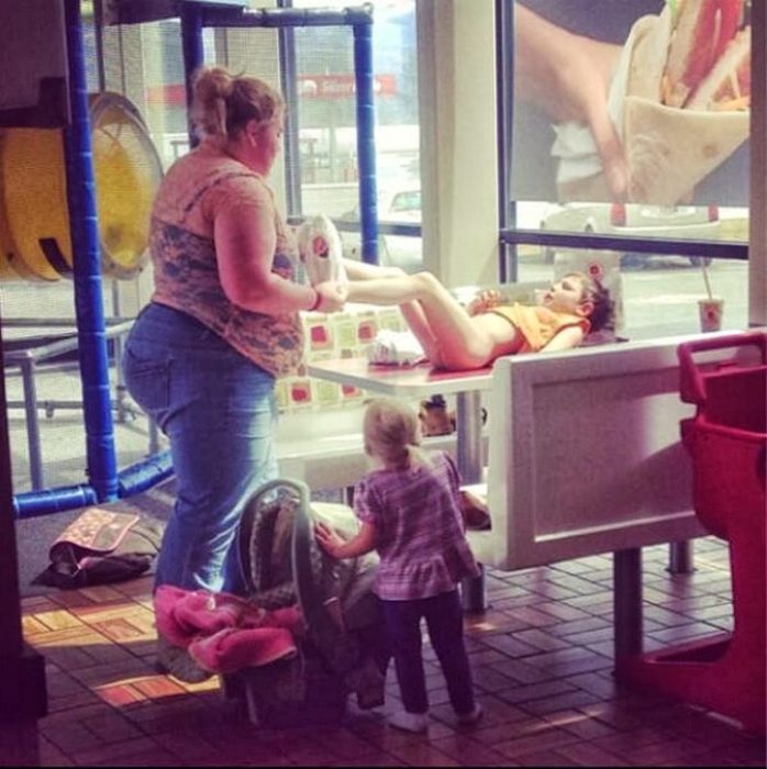 mujer cambiando pantalones a su hija sobre una mesa