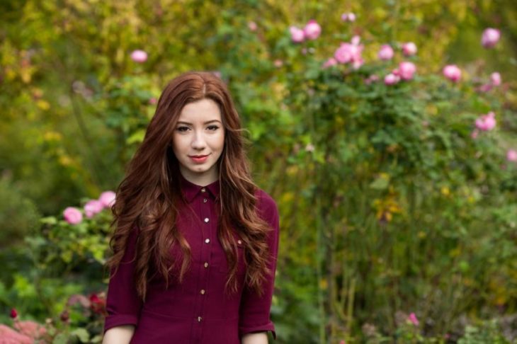 mujer pelirroja en campo con flores