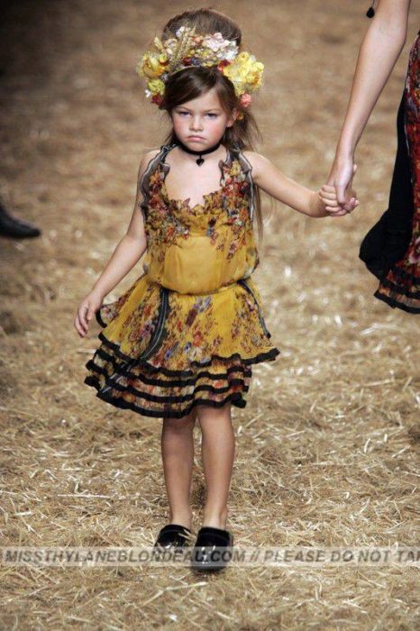 niña con corona de flores en una pasarela