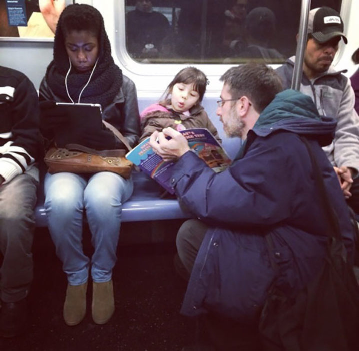 papá en el metro leyendo con su hija 