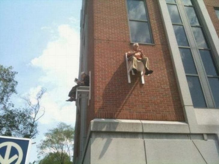 señor sentado en una silla pegada a muro de edificio