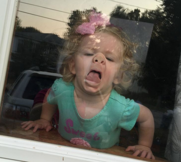 niña con el rostro pegado a un vidrio